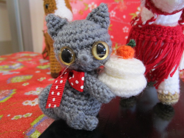 猫のあんじゅさんが鏡餅を持っています。